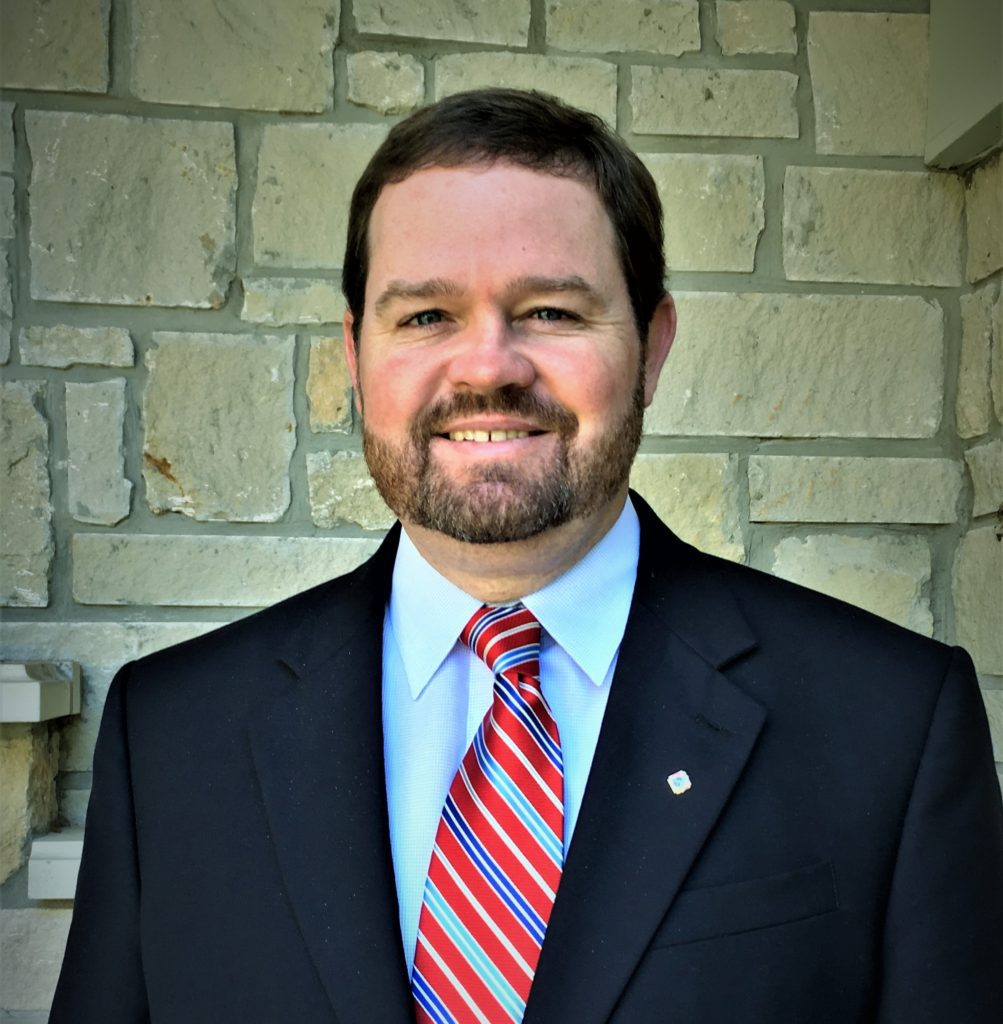 A man in suit and tie standing next to a wall.